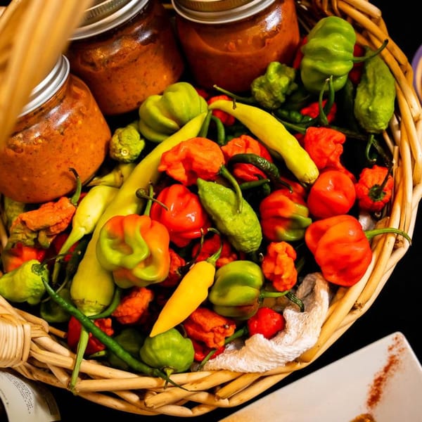 A basket filled with colorful Jamaican peppers and jars of Irie Diner's hot sauce.