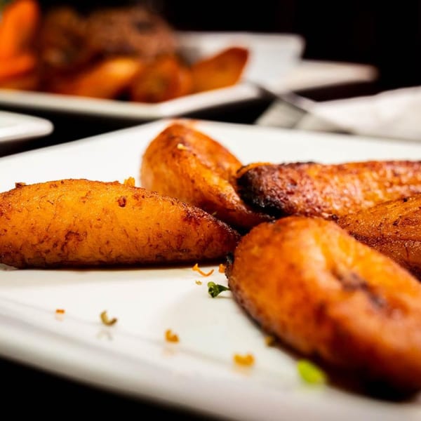 Close-up of golden-brown fried plantains on a white plate at Irie Diner Caribbean Restaurant.