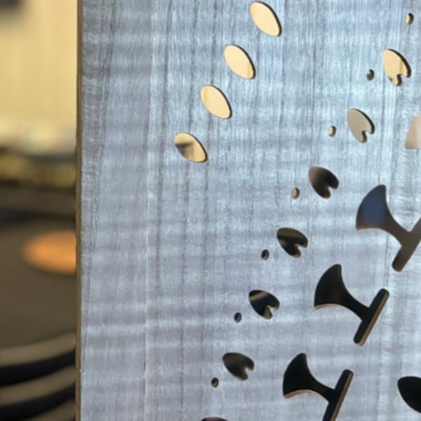 Close-up of a decorative wooden panel with cutouts of oval and heart shapes, revealing a blurred background.