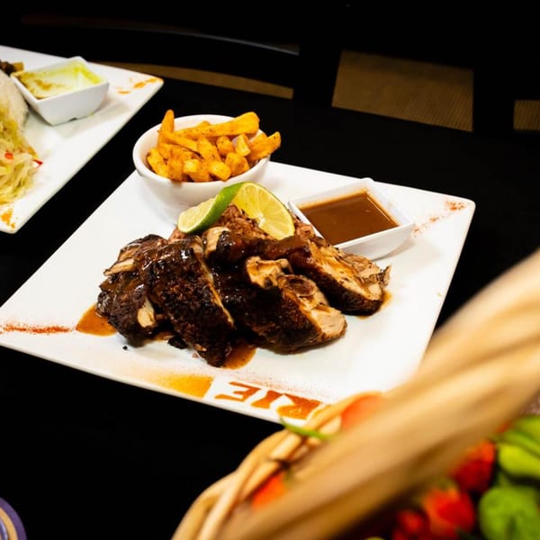 Platter of sliced jerk chicken with lime, fries, and sauce, from Irie Diner.