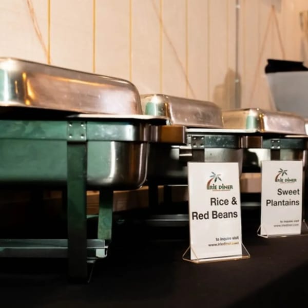 Chafing dishes with signs for Rice & Red Beans and Sweet Plantains at Irie Diner Caribbean Restaurant.