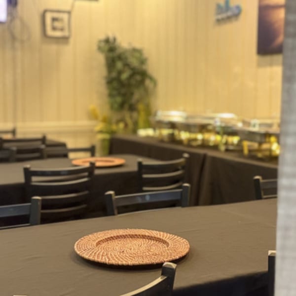 Dining room with black-clothed tables, chairs, and a buffet line, ready for guests at Irie Diner.