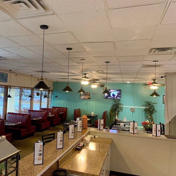Interior of Irie Diner Caribbean Restaurant with red booths, teal walls, and a counter with menus.