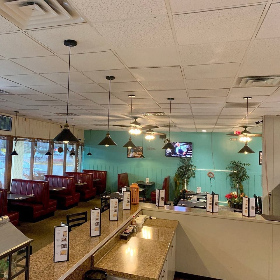 Interior of Irie Diner Caribbean Restaurant with red booths, teal walls, and a counter with menus.